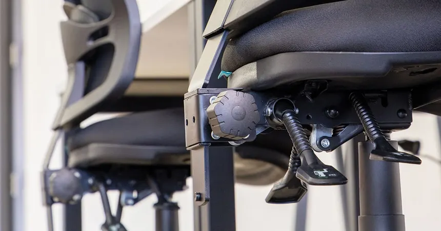 The adjustment levers on the underside of an office chair seat.