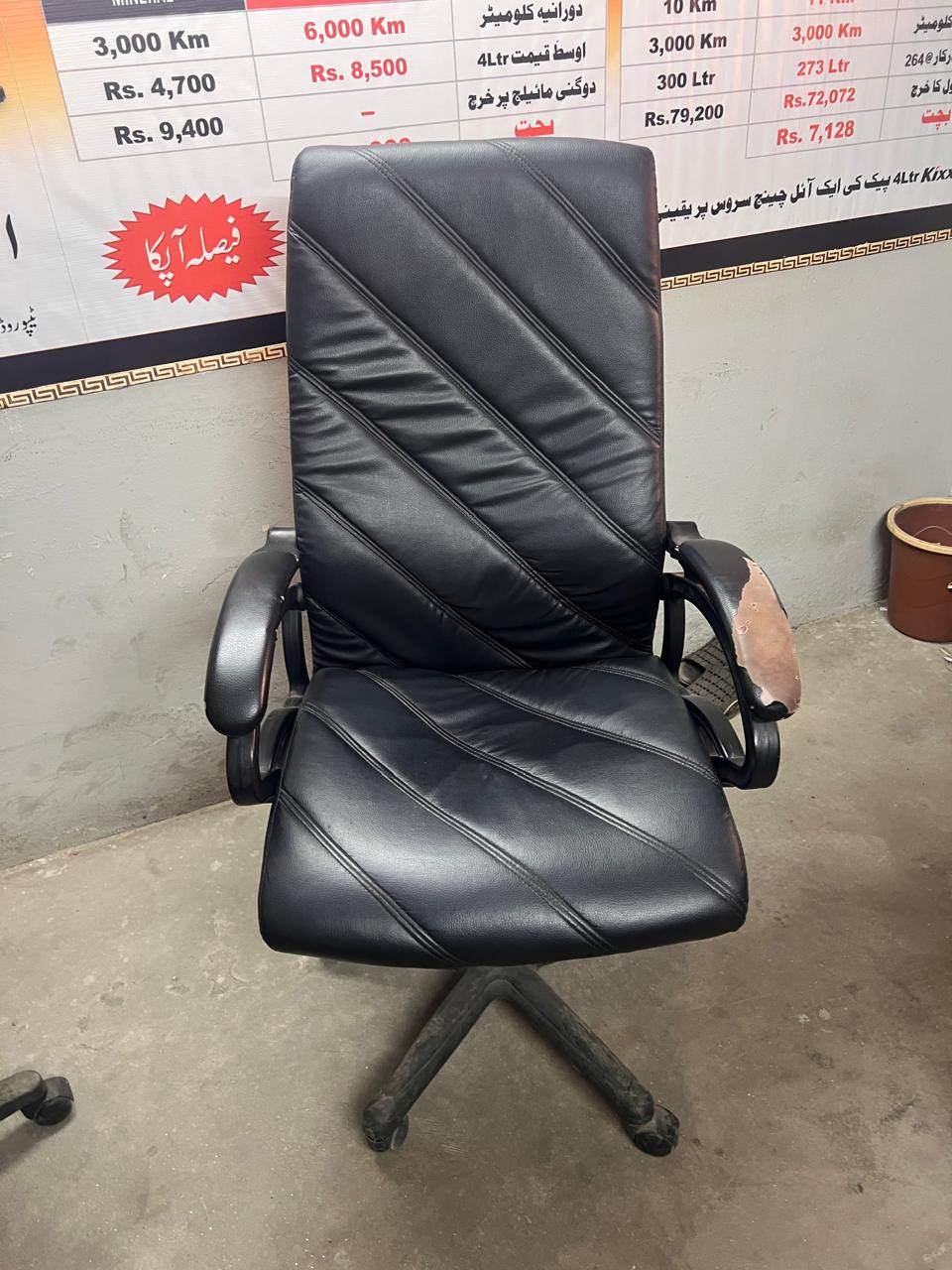 An executive chair freshly covered in black leather with diagonal stitched panels across the back and seat.