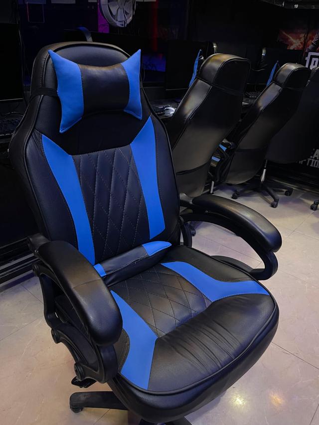 A gaming chair rebuilt in black and blue leather with diamond-stitched panels, back in service on the floor of a gaming café.