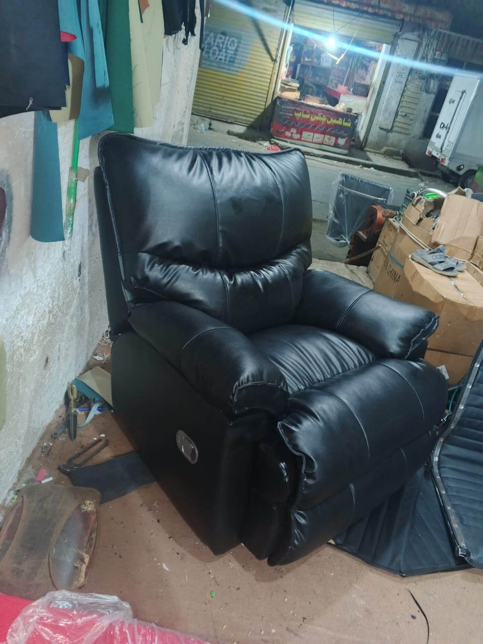 The recliner armchair after repair, reupholstered in black leather with refilled seat and back cushions.